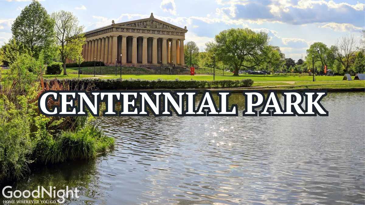 A wide view of Centennial Park, featuring the iconic Parthenon-like structure reflecting in a tranquil water surface, surrounded by lush green trees. The scene captures people leisurely picnicking, walking, and enjoying the serene park atmosphere.