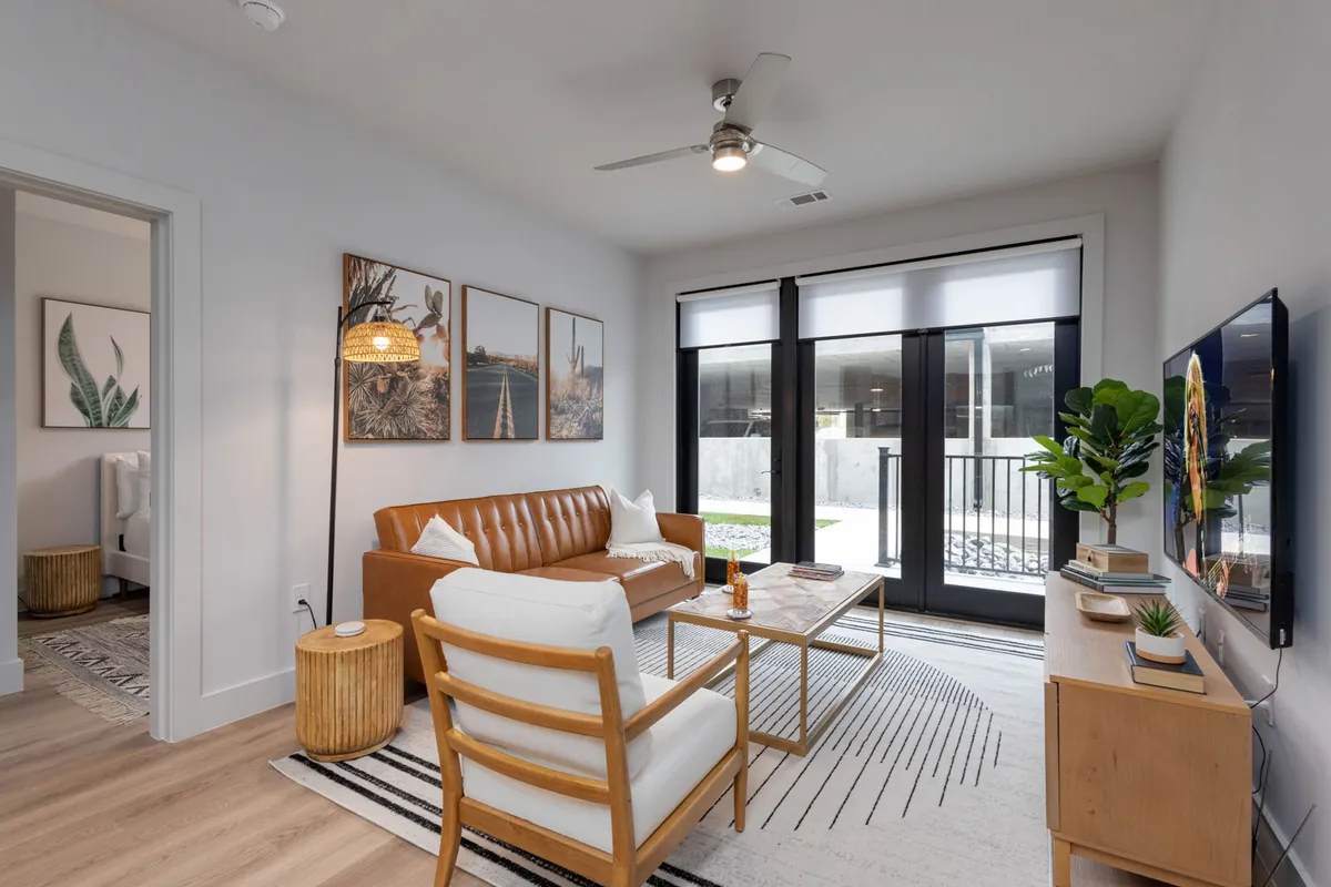 A contemporary living area with a leather sofa, a central coffee table, wall art, and large windows that provide city views and ample natural light. The layout is open and flexible, providing options for both group and intimate settings.